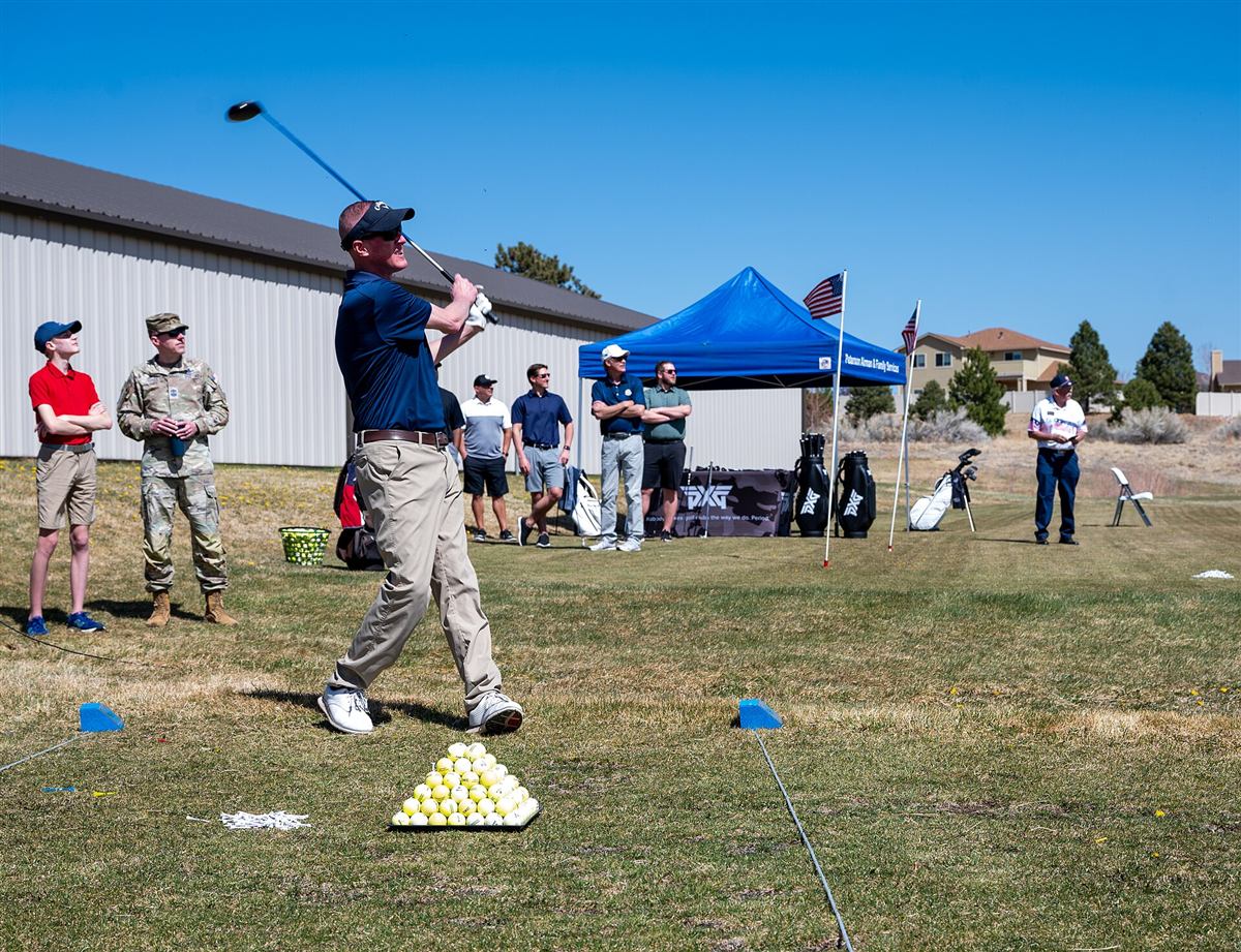 Golfactiviteit buiten op een event, met een tent op de achtergrond